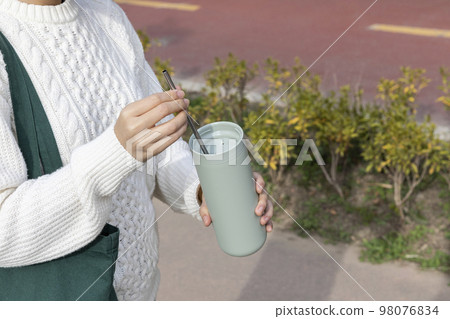 eco friendly habits hand gesture_holding a tumbler and putting in a stainless steel straw eco friendly habits hand gesture_holding a tumbler and putting in a stainless steel straw 98076834