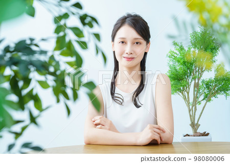 Woman smiling in a room surrounded by greenery 98080006