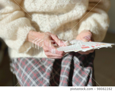 Elderly woman's hand looking at a new year's card Elderly woman's hand looking at a new year's card 98082282