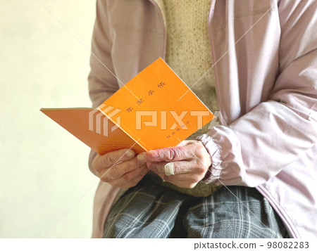 Elderly woman's hand holding a pension book Elderly woman's hand holding a pension book 98082283