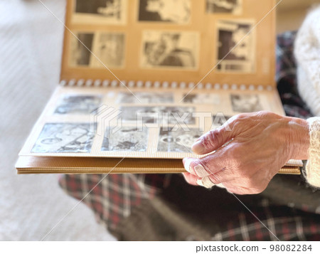 Elderly woman's hand looking at black and white photo album Elderly woman's hand looking at black and white photo album 98082284