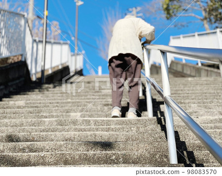 一位老婦人扶著扶手從下面上樓梯 98083570