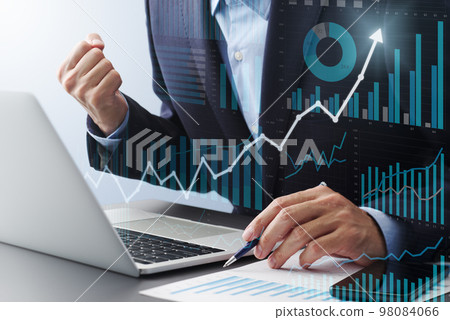 A man in a suit rejoicing in success. A laptop and a number of report graphs. Image of data analysis and goal achievement A man in a suit rejoicing in success. A laptop and a number of report graphs. Image of data analysis and goal achievement 98084066