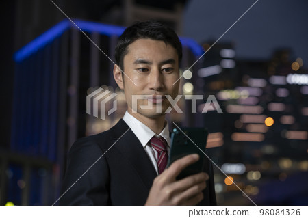 晚上看智能手機屏幕的商人 98084326