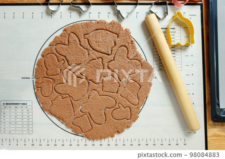 Flat lay of rolled dough for homemade cookies with squeezed cookies of various shapes 98084883