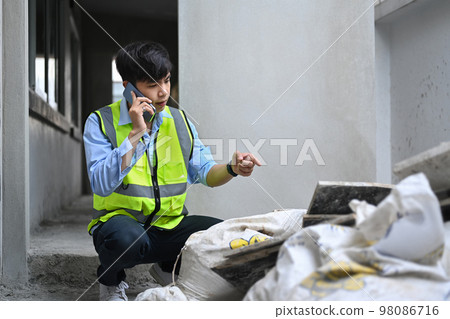 Young asian man inspectors talking on mobile phone and checking building material at construction site Young asian man inspectors talking on mobile phone and checking building material at construction site 98086716