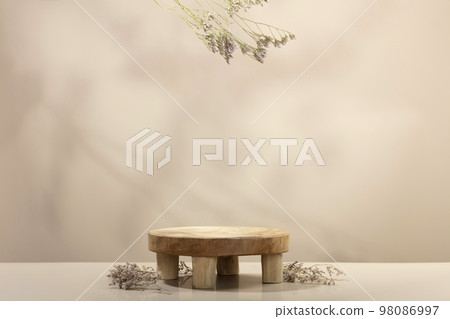Empty round wooden podium for product presentation and dry leaves on beige background for cosmetic product mockup 98086997