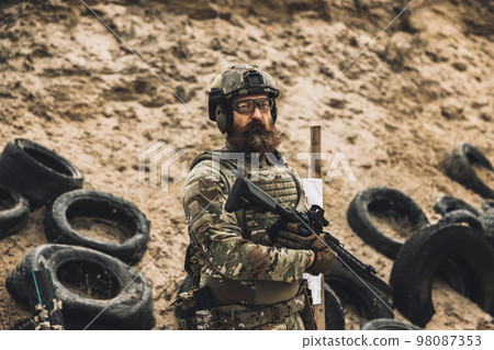 Mature soldier standing near the shooting target with rifle in hands Mature soldier standing near the shooting target with rifle in hands 98087353