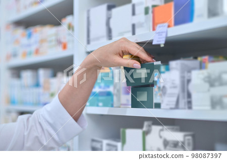 Close up picture of pharmacists hand taking a box with medicine 98087397