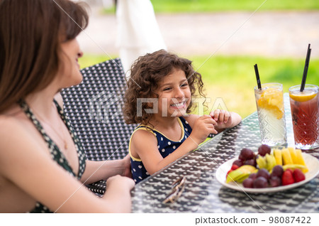Mom and daughter having fruits and looking happy 98087422
