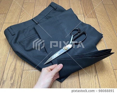 A hand lifting the hem of a suit's trousers to hem it 98088891
