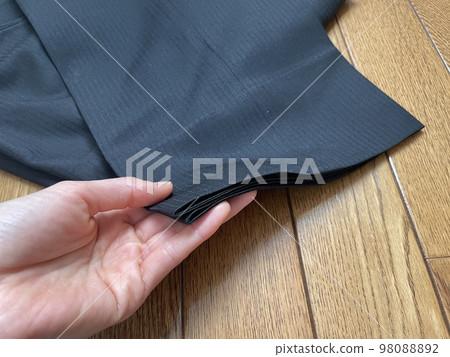 A hand that lifts the hem of a suit's trousers 98088892