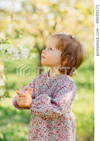 a pretty little girl by a flowering tree in a spring garden a pretty little girl by a flowering tree in a spring garden 98089572