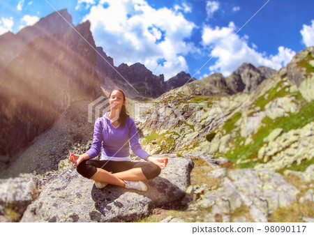 Woman sitting in lotus position on stone in nature and practicing yoga Woman sitting in lotus position on stone in nature and practicing yoga 98090117