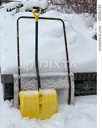 Yellow snow shovel standing in the snow Yellow snow shovel standing in the snow 98090185
