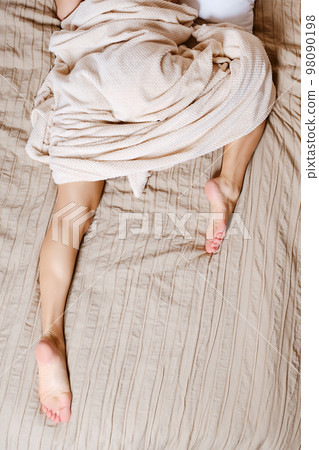 Woman sleeps lying on her stomach with one leg tucked under her Woman sleeps lying on her stomach with one leg tucked under her 98090198