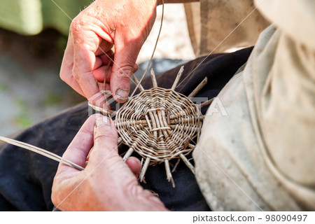 Hands of the senior craftsman while weaving wicker basket. Traditional Slovak folk craft. Hands of the senior craftsman while weaving wicker basket. Traditional Slovak folk craft. 98090497