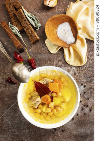 Hot spicy soup with chickpeas, onions in ceramic bowl on a dark background close-up. 98090824