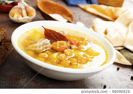 Hot spicy soup with chickpeas, onions in ceramic bowl on a dark background close-up. Hot spicy soup with chickpeas, onions in ceramic bowl on a dark background close-up. 98090828