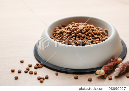 A bowl of dog food on a wooden floor. 98090927