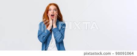 Oh my gosh, amazing. Surprised speechless redhead woman standing starled and shocked, touch face, drop jaw and stare camera fascinated, got job, won prize, standing white background Oh my gosh, amazing. Surprised speechless redhead woman standing starled and shocked, touch face, drop jaw and stare camera fascinated, got job, won prize, standing white background 98091064