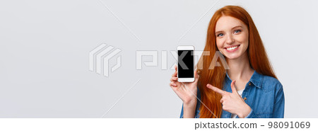 Girl found her date on this app. Cheerful attractive redhead woman with blue eyes give advice, showing smartphone display and pointing finger mobile screen, smiling give recommendation Girl found her date on this app. Cheerful attractive redhead woman with blue eyes give advice, showing smartphone display and pointing finger mobile screen, smiling give recommendation 98091069
