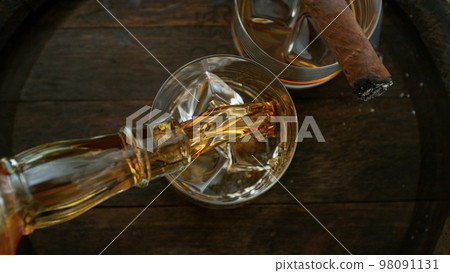 Close-up of pouring whiskey or rum on old wooden barrel Close-up of pouring whiskey or rum on old wooden barrel 98091131