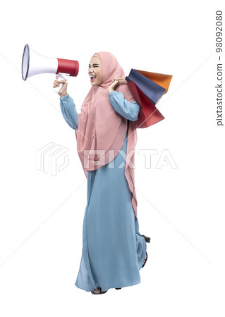 Asian Muslim woman in veil holding megaphone and shopping bags 98092080