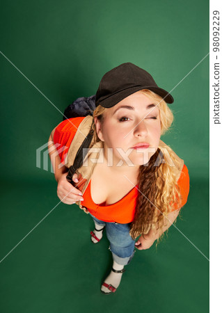 Portrait of blonde woman in cap with backpack posing over green studio background. Travelling. Vacation time Portrait of blonde woman in cap with backpack posing over green studio background. Travelling. Vacation time 98092229