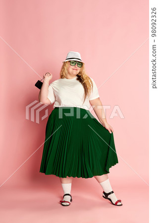 Portrait of stylish woman posing over pink studio background. Comfortable, fashionable clothes 98092326