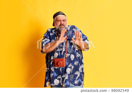 Portrait of fat mature man in stylish shirt posing over bright yellow studio background. Tourism. Refusal face Portrait of fat mature man in stylish shirt posing over bright yellow studio background. Tourism. Refusal face 98092549
