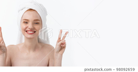 Beautiful caucasian woman applying mask on her face with two fingers sign white background. 98092659