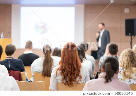 Speaker giving a talk in conference hall at business event. Rear view of unrecognizable people in audience at the conference hall. Business and entrepreneurship concept 98093140