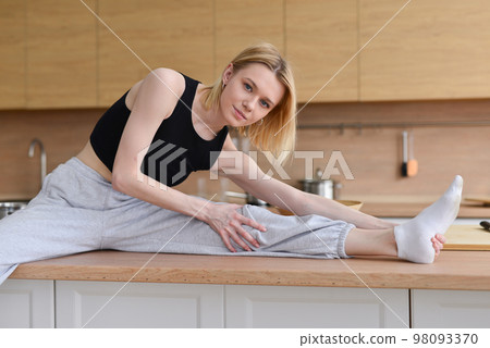 Woman sitting on table doing stretching Woman sitting on table doing stretching 98093370