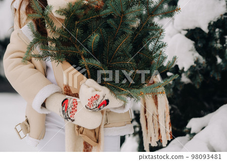 A girl in a winter forest with a bouquet of fir branches. Snowy winter 98093481