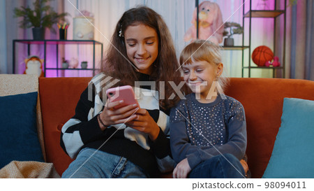 Teen sisters kids celebrate success win scream rejoices while doing online shopping on smartphone 98094011