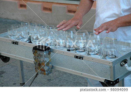 Street musician playing on glass harp Street musician playing on glass harp 98094099