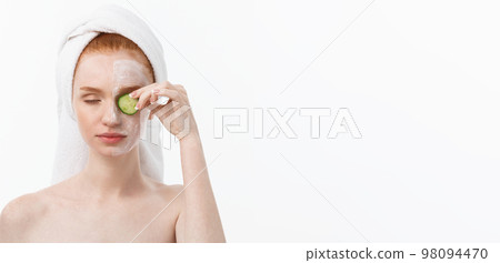 Attractive Young Woman with beautiful clean skin. White mask and cucumbers. Beauty treatments and cosmetology spa therapy. White background 98094470