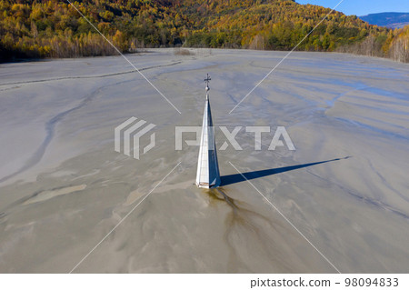 Aerial view of a church tower with cross, buried under mud and mining residuals 98094833