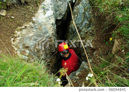 Caver descends in a cave 98094845