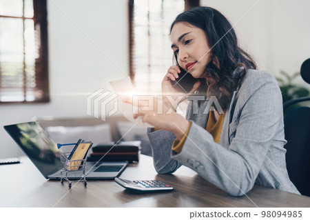 Young Asian Woman checking bills, bank account balance, taxes and calculating expenses at home Young Asian Woman checking bills, bank account balance, taxes and calculating expenses at home 98094985