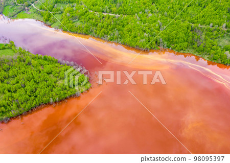 Aerial view of red waste water and green forest 98095397