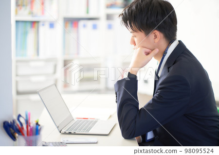 一位年輕的商務人士在辦公室裡看著 PC 屏幕思考 一位年輕的商務人士在辦公室裡看著 PC 屏幕思考 98095524