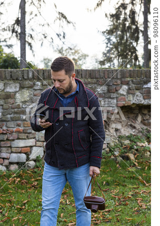 Photographer with vintage analogue film camera and smartphone outdoors Photographer with vintage analogue film camera and smartphone outdoors 98096110