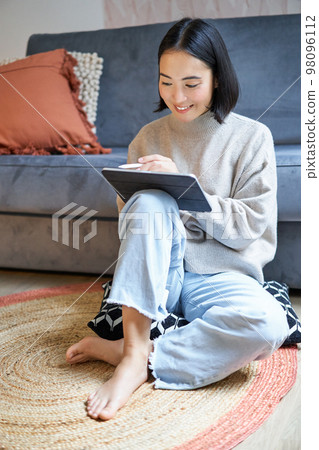 Vertical shot of cute asian girl in cozy home, drawing on her digital tablet with pen, designer working on project Vertical shot of cute asian girl in cozy home, drawing on her digital tablet with pen, designer working on project 98096112