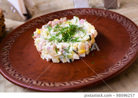 traditional Russian salad with peas and mayonnaise, served in a cylinder on a clay plate traditional Russian salad with peas and mayonnaise, served in a cylinder on a clay plate 98096257