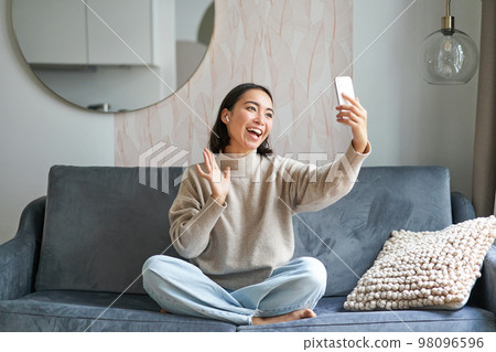 Beautiful chatty girl video chats, making video on smartphone, taking selfie, smiling at mobile phone camera Beautiful chatty girl video chats, making video on smartphone, taking selfie, smiling at mobile phone camera 98096596