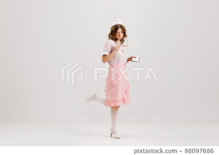 Portrait of young female waitress, sensual woman in retro american fashion style of 70s, 80s in action motion over grey background. Portrait of young female waitress, sensual woman in retro american fashion style of 70s, 80s in action motion over grey background. 98097686