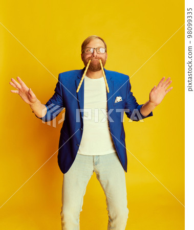 Joyful middle age man in bright blue jacket and trousers having fun isolated over yellow background. Concept of fashion, beauty, positive emotions 98099335