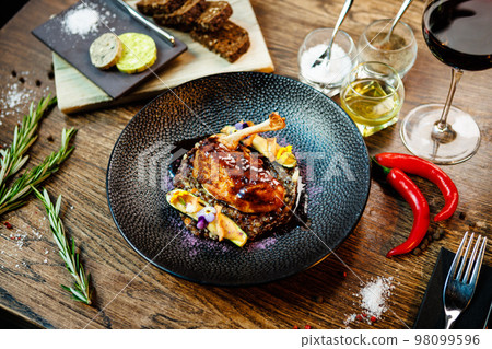 Corn chicken supreme. Beluga lentils, Old Ammerlander cheese, mini zucchini, red wine sauce. Delicious healthy traditional food closeup served for lunch in modern gourmet cuisine restaurant 98099596